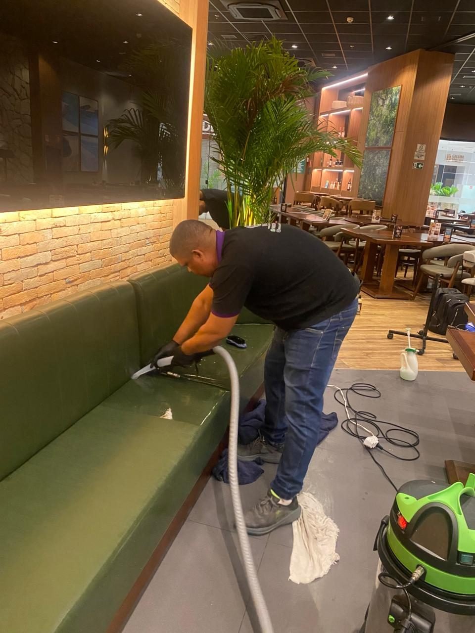 Limpeza de sofá verde com equipamento profissional em Maceió